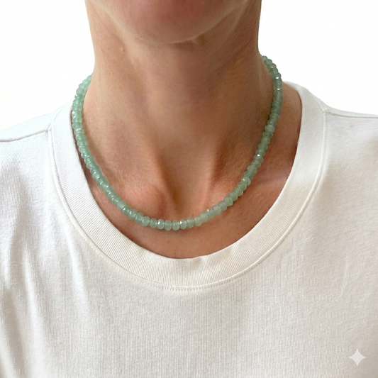 Person wearing a green beaded necklace against a white background