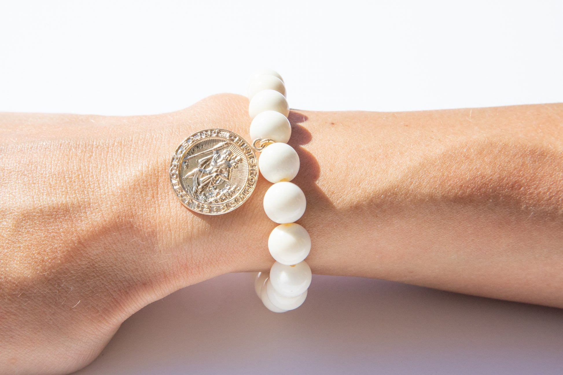 White Bone Bead Bracelet Adorned With a  Yellow Gold Filled St Christopher Medallion Coin Charm Featured on Arm